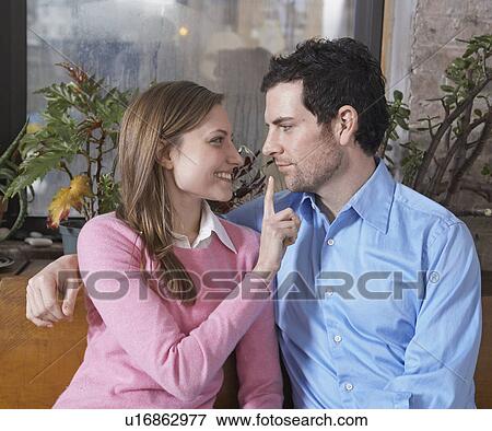 Stock Photo - Woman Holding Finger on Boyfriend's Mouth. Fotosearch