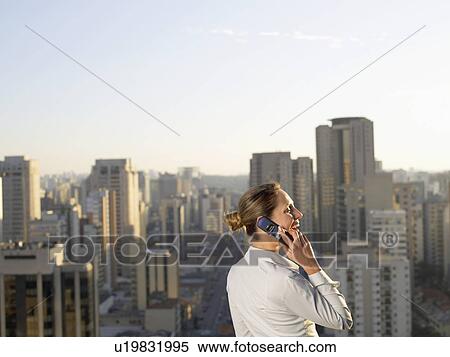 Businesswoman talking on cell phone, city in background, Sao Paolo, Brazil View Large Photo Image Stock Photography - Businesswoman talking on cell phone, city in background, Sao Paolo, Brazil. Fotosearch
