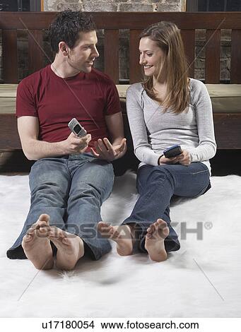 Picture - Couple Using Mobile Phones on Floor. Fotosearch