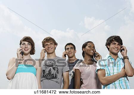Five teenagers on mobile phones (low angle view) View Large Photo Image Stock Image - Five teenagers on mobile phones (low angle view). Fotosearch