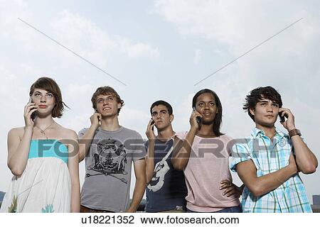 Five teenagers on mobile phones (low angle view) View Large Photo Image Stock Image - Five teenagers on mobile phones (low angle view). Fotosearch