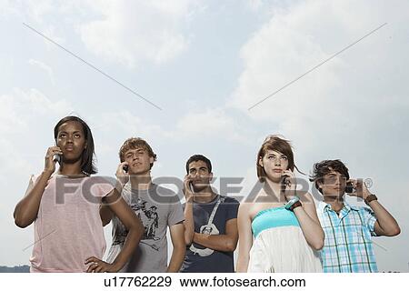 Five teenagers on mobile phones (low angle view) View Large Photo Image Stock Photo - Five teenagers on mobile phones (low angle view). Fotosearch