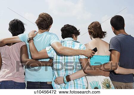 Stock Image - Five teenagers standing side by side (rear view). Fotosearch