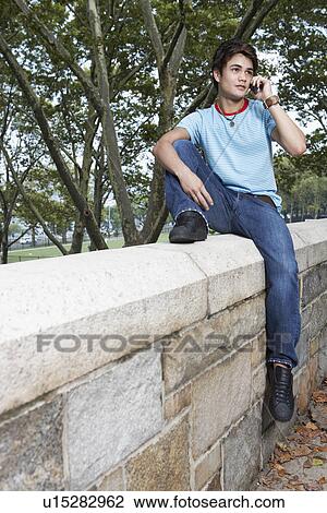 Teenage boy sitting on fence and talking on mobile phone View Large Photo Image Stock Image - Teenage boy sitting on fence and talking on mobile phone. Fotosearch