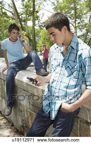 Teenage boys using mobile phones View Large Photo Image Stock Image - Teenage boys using mobile phones. Fotosearch