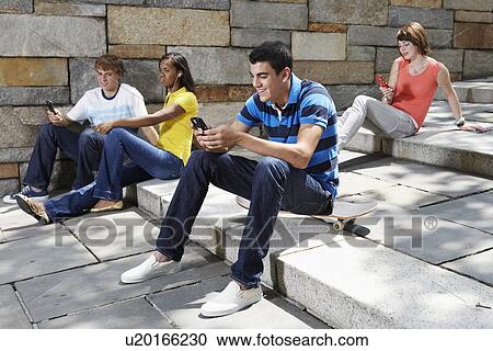 Stock Image - Teenagers using mobile phones. Fotosearch