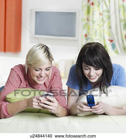 Stock Image - Two Young Women Text Messaging. Fotosearch