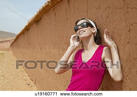 Stock Image - Woman Talking on Phone by Wall. Fotosearch
