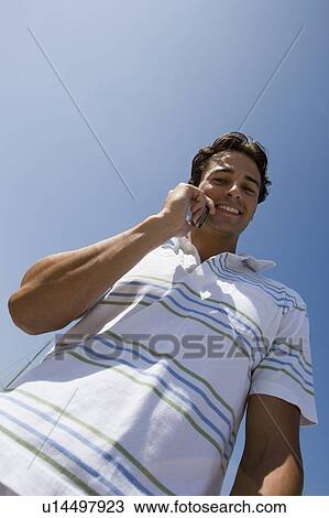 Young adult man talking on mobile phone, Low Angle View View Large Photo Image Stock Image - Young adult man talking on mobile phone, Low Angle View. Fotosearch
