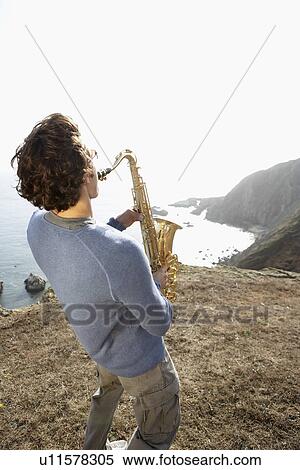 Man playing saxophone on cliff (rear view) View Large Photo Image Stock Photography - Man playing saxophone on cliff (rear view). Fotosearch