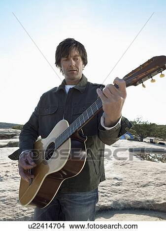Picture - Mid adult man playing acoustic guitar. Fotosearch
