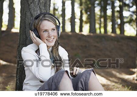 Stock Photograph - Teenage girl listening to headphones in woods. Fotosearch