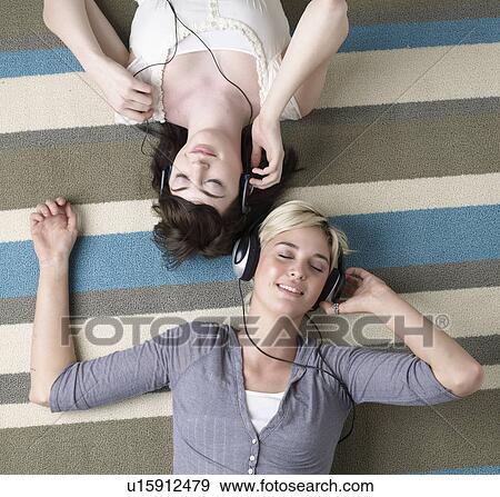 Stock Photo - Two Young Women Listening to Headphones. Fotosearch