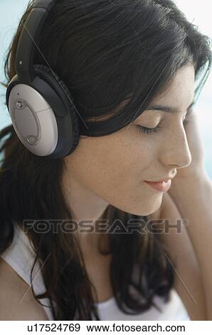 Stock Photo - Young woman listening to headphones. Fotosearch