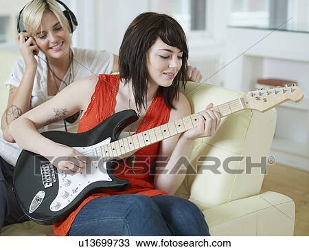 Stock Image - Young Women Playing Electric Guitar. Fotosearch