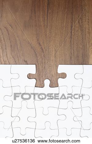 Stock Photograph - Jigsaw puzzle on wooden background, piece missing. Fotosearch