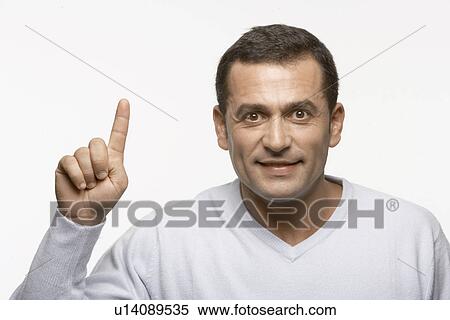 Stock Photography - Mid adult man holding index finger up. Fotosearch