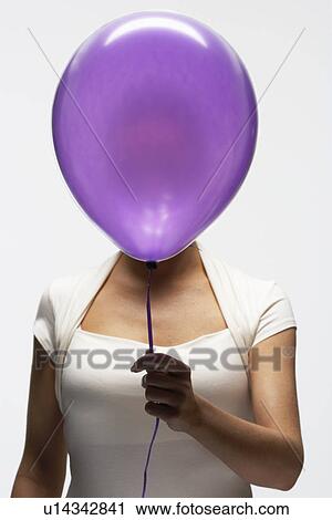 Stock Image - Woman holding balloon in front of her face. Fotosearch