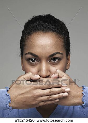 Stock Image - Young woman covering mouth with hands. Fotosearch