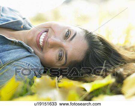 Mid adult woman lying on autumn leaves, portrait View Large Photo Image Stock Image - Mid adult woman lying on autumn leaves, portrait. Fotosearch