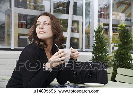 Stock Photography - Woman drinking coffee at café. Fotosearch
