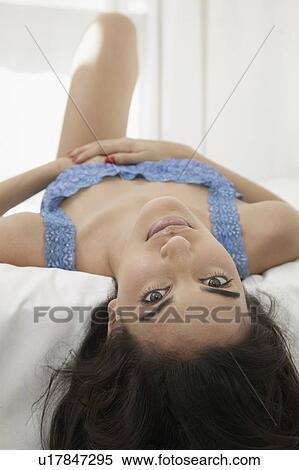 Stock Photography - Young woman lying on bed (portrait). Fotosearch