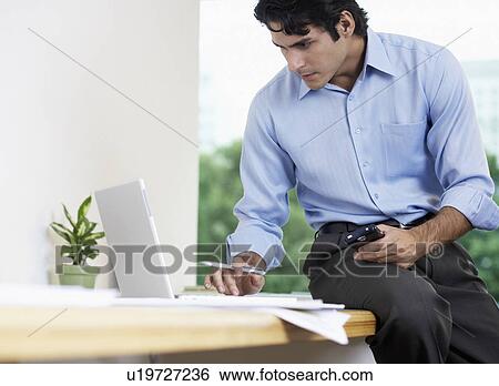 Businessman with PDA using laptop (low angle view) View Large Photo Image Stock Photograph - Businessman with PDA using laptop (low angle view). Fotosearch