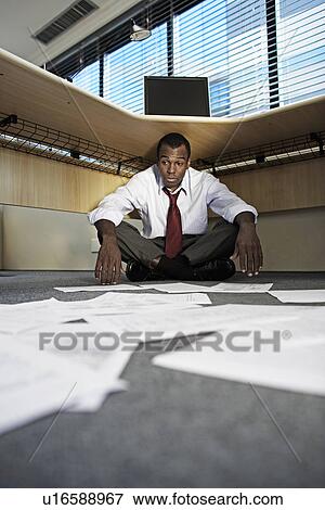Stock Photo - Mid Adult Man Doing Paperwork Under Desk. Fotosearch