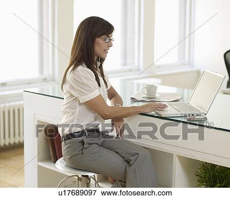 Mid-Adult Woman Using Laptop in Office View Large Photo Image Stock Photo - Mid-Adult Woman Using Laptop in Office. Fotosearch