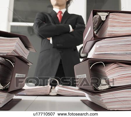 Stock Photo - Office Worker Standing by Files. Fotosearch