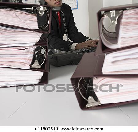 Office Worker Typing While on Phone View Large Photo Image Stock Photo - Office Worker Typing While on Phone. Fotosearch