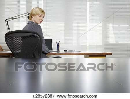 Young businesswoman sitting at desk View Large Photo Image Stock Photo - Young businesswoman sitting at desk. Fotosearch