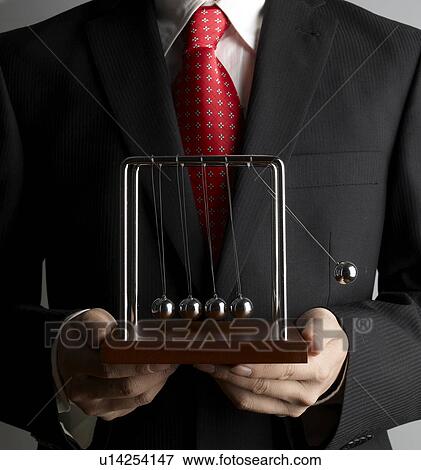 Stock Photo - Businessman Holding Newton's Cradle. Fotosearch