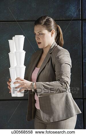 Stock Photo - Businesswoman carrying stacks of takeout coffees. Fotosearch