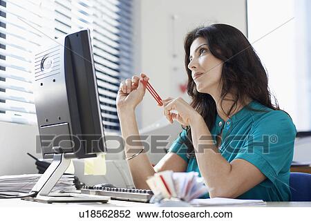 Stock Image - Female office worker day dreaming. Fotosearch