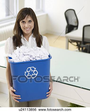 Stock Photograph - Mid-Adult Woman Holding Paper Recycling Bin. Fotosearch