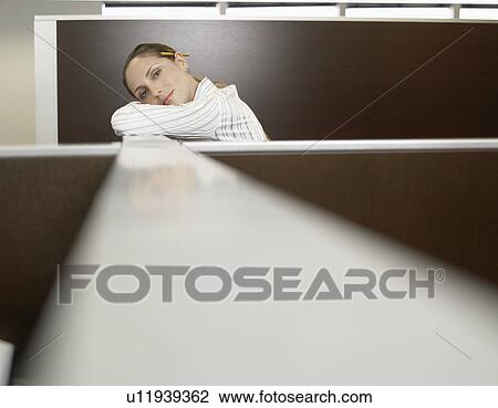 Stock Image - Office worker leaning against partition wall (portrait). Fotosearch
