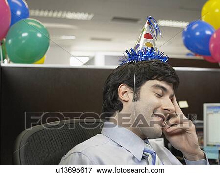 Stock Photo - Office worker wearing party hat. Fotosearch