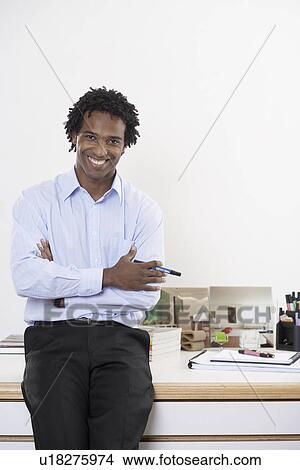 Picture - Young man leaning on desk (portrait). Fotosearch