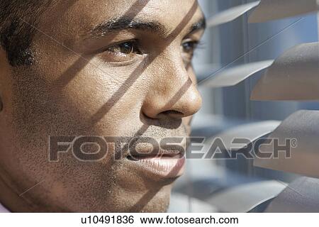 Young man looking through blinds View Large Photo Image Stock Photograph - Young man looking through blinds. Fotosearch