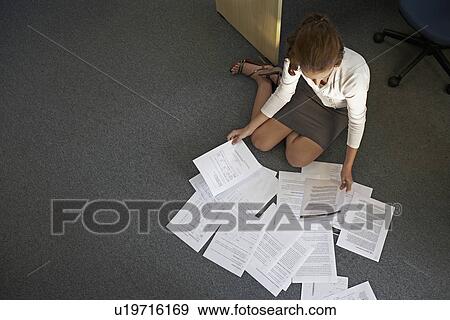 Stock Photo - Young Woman Doing Paperwork on Floor. Fotosearch