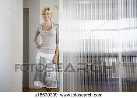 Stock Photo - Young woman leaning on glass wall. Fotosearch