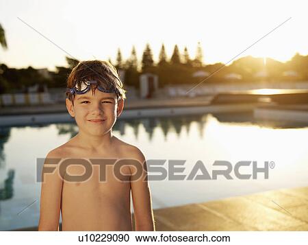 Stock Image - Boy with goggles standing by swimming pool. Fotosearch