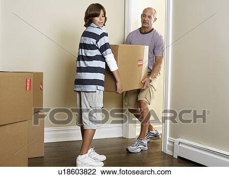 Father and son carrying cardboard box in room View Large Photo Image Stock Image - Father and son carrying cardboard box in room. Fotosearch