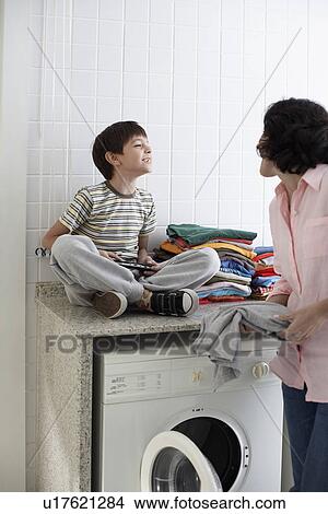 Son and mother grinning to each other in laundry room View Large Photo Image Picture - Son and mother grinning to each other in laundry room. Fotosearch