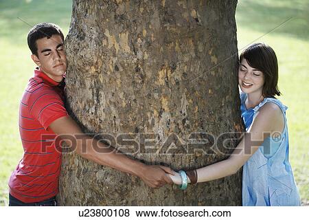 Stock Photo - Teenage couple hugging tree. Fotosearch