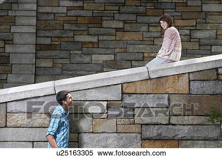 Stock Photography - Teenage girl and boy by stone wall. Fotosearch
