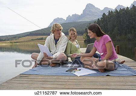 Stock Photo - Three Teenagers Studying at Lake. Fotosearch