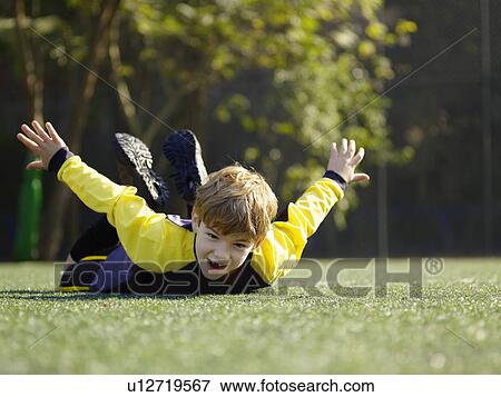 Stock Photo - Young boy lying on grass. Fotosearch