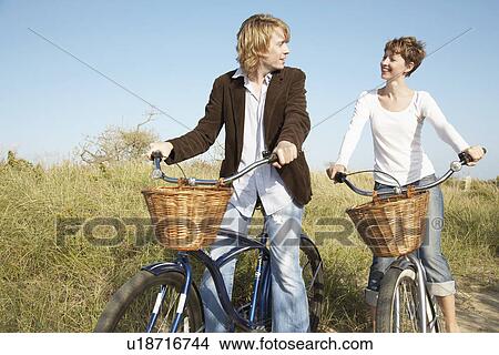 Picture - Couple cycling in field. Fotosearch